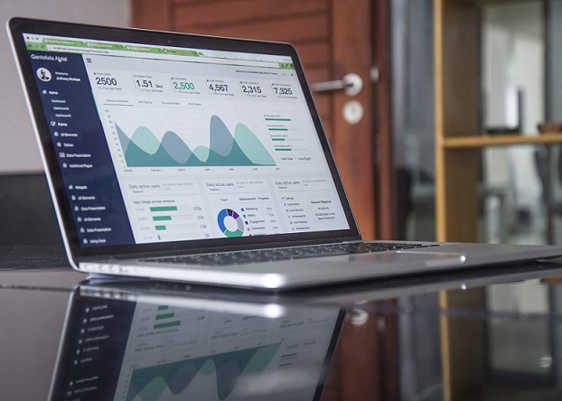 Lap top computer on glass top desk with financial report on the screen.